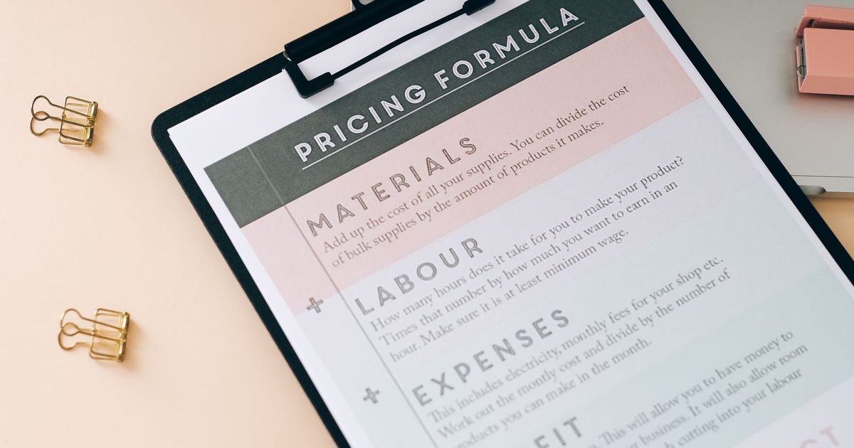 A pricing formula worksheet on a clipboard next to a laptop, used to plan a wedding budget