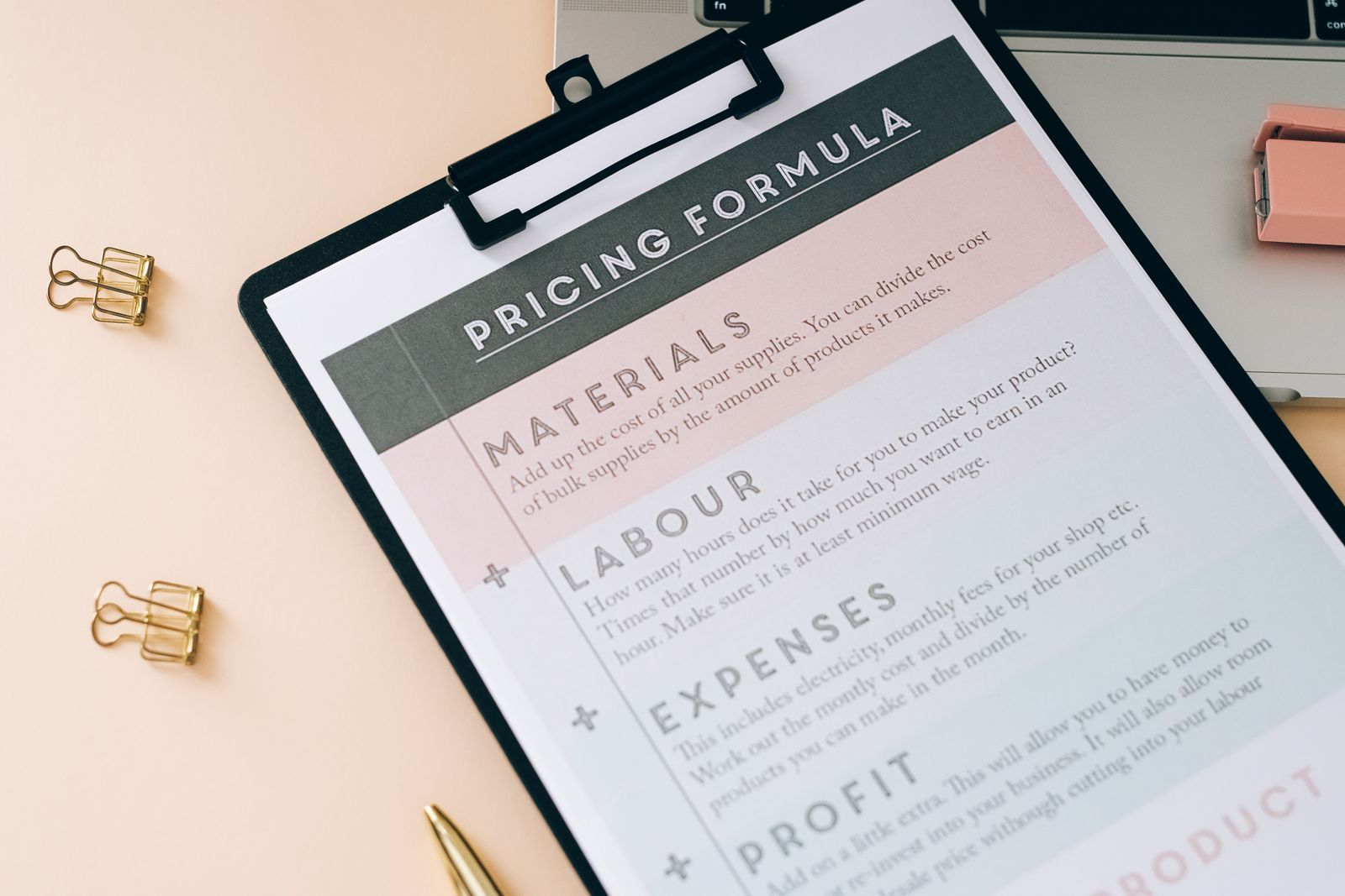 A pricing formula worksheet on a clipboard next to a laptop, used to plan a wedding budget