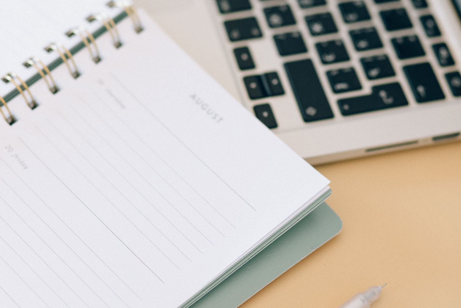 An open notebook next to a laptop, used to plan out a wedding budget breakdown