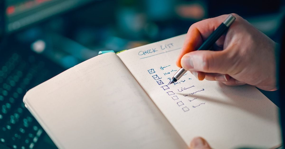 Hand writing items into a notebook checklist for task management