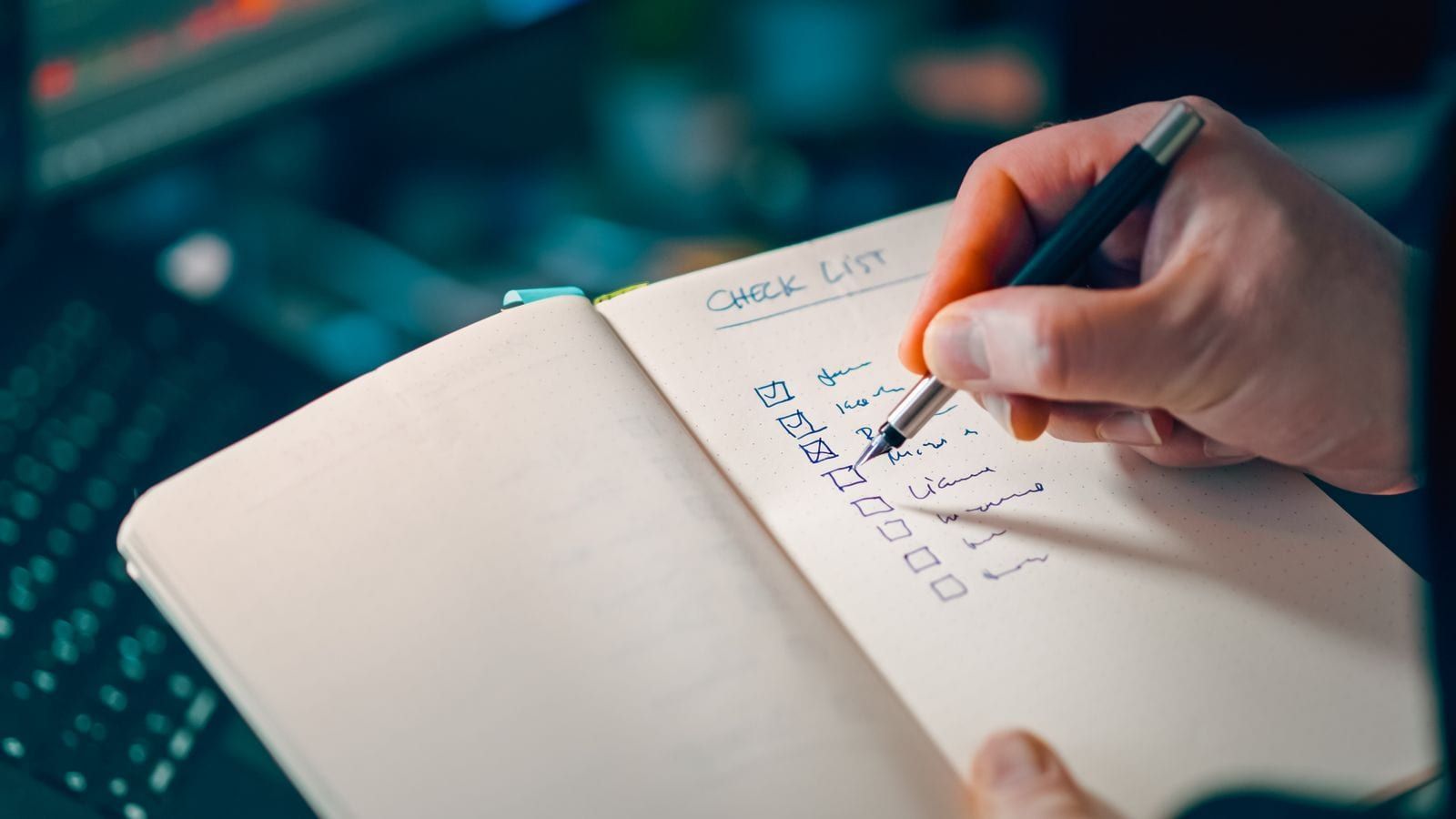 Hand writing items into a notebook checklist for task management