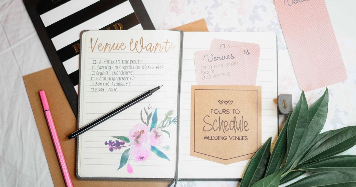 Flat lay of a wedding planning journal, dried leaves and stationery on a table