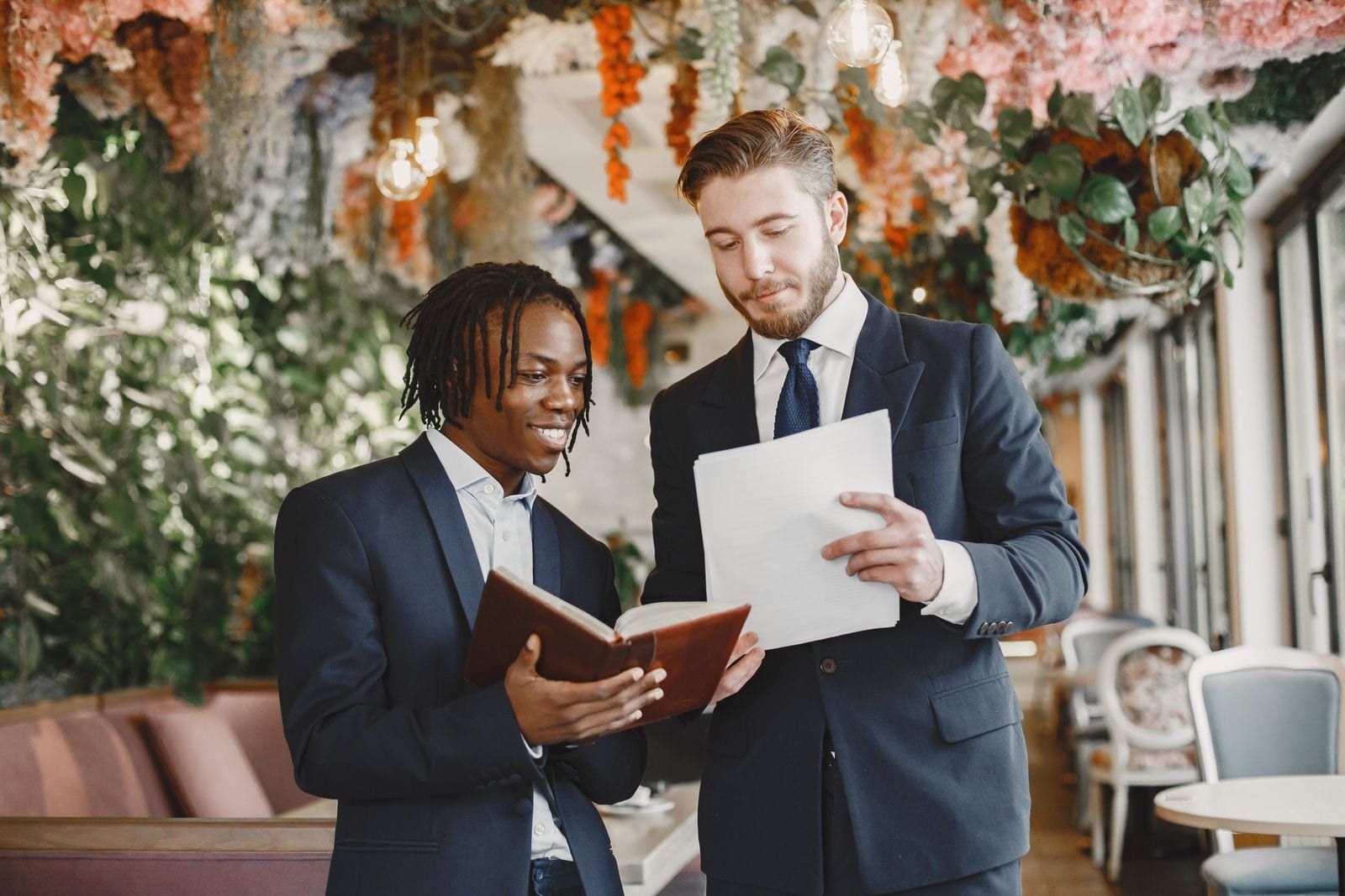 Two suppliers in suits reviewing paperwork together at a decorated reception venue
